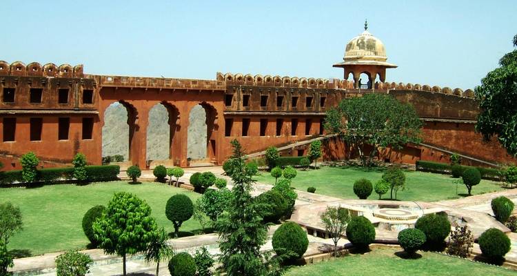 Fort en grès rouge avec un jardin au premier plan.