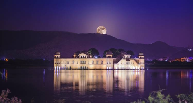 Palais du lac illuminé la nuit avec la pleine lune dans le ciel.