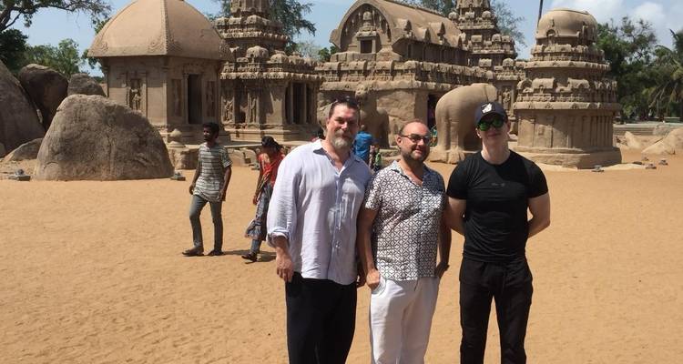 Drie mensen die voor een stenen tempelstructuur staan.