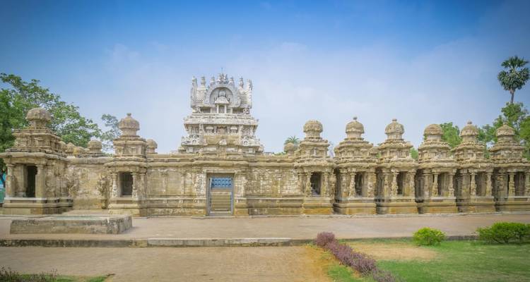 Verzierter Tempel mit grauem Mauerwerk unter blauem Himmel.