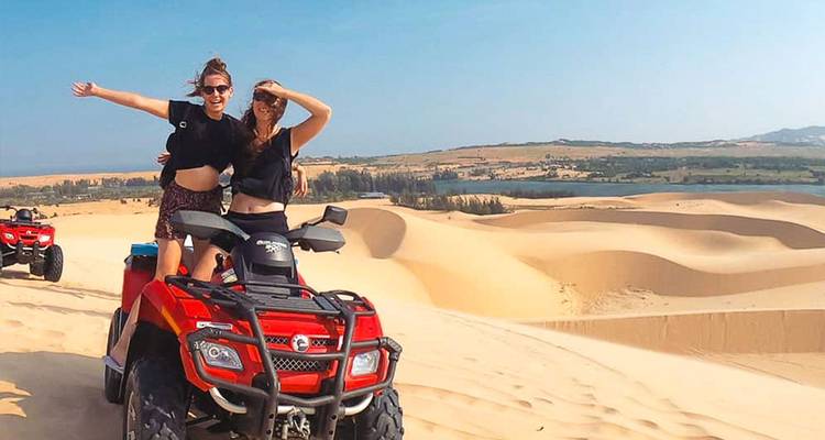 Deux personnes sur un VTT dans les dunes de sable.
