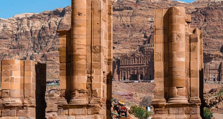 Antike Ruinen mit Säulen und bergiger Kulisse.