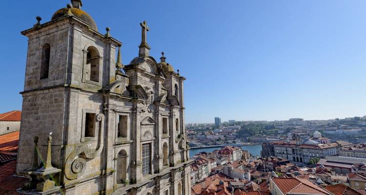 Vista de una iglesia con una cruz en la parte superior, con vista a una ciudad.