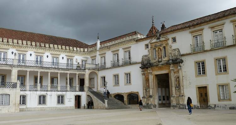 Patio histórico con una persona caminando, con arquitectura clásica.
