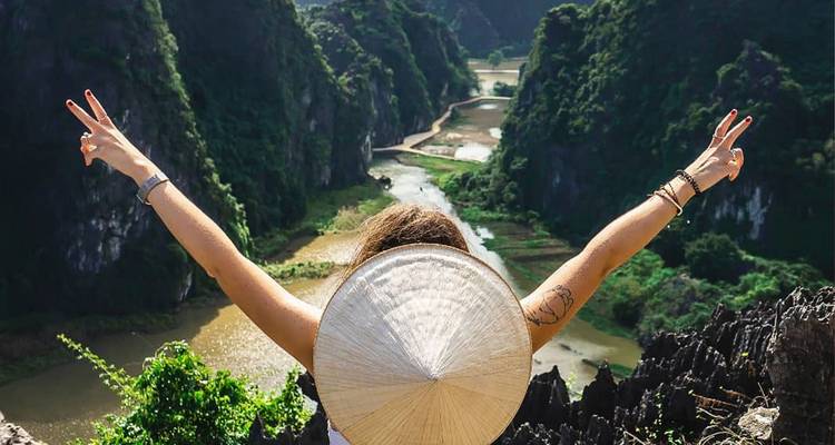 Personne avec les bras levés admirant un paysage verdoyant époustouflant.