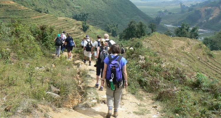 Groupe de randonneurs marchant le long d'un sentier dans des champs en terrasses.