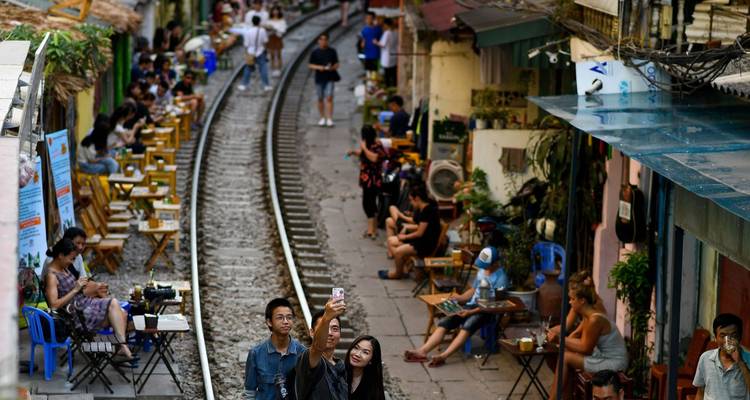 People taking selfies at a train street cafe.