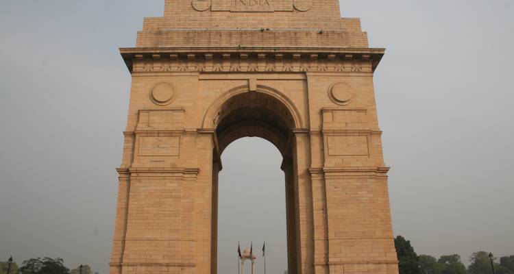 De India Gate op een open plein met een heldere hemel.