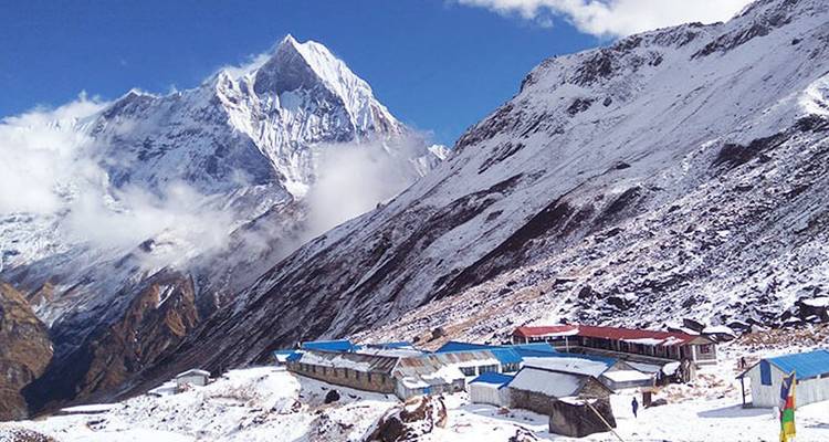 Schnebedeckte Gipfel mit Hütten im Vordergrund.