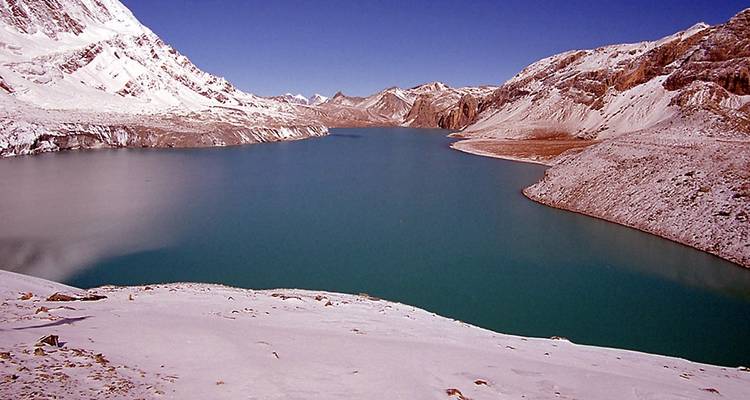 Großer See umgeben von schneebedeckten Bergen.