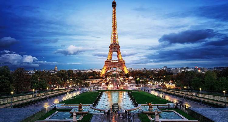 Vue de la Tour Eiffel avec une fontaine illuminée au premier plan.
