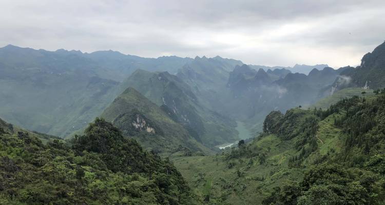 Weite Berglandschaft mit sanften Hügeln und bewölktem Himmel.