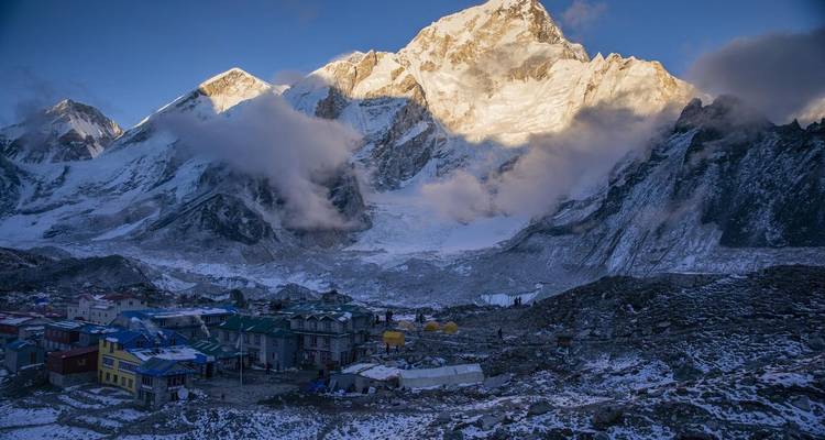 Village de montagne avec des sommets enneigés au loin.