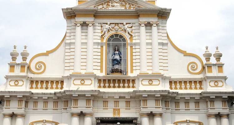 Die Fassade einer historischen weißen Kirche mit einer Statue in der Mitte.