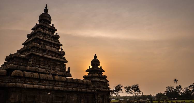 Alte Steintempel, die sich gegen einen Abendhimmel abzeichnen.