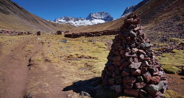 Bergachtig terrein met stenen markeringen en verre bergtoppen.