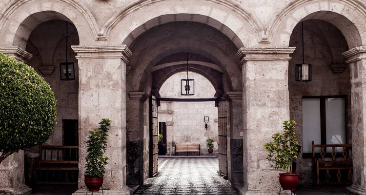 Arches en pierre et cour avec des plantes en pot.