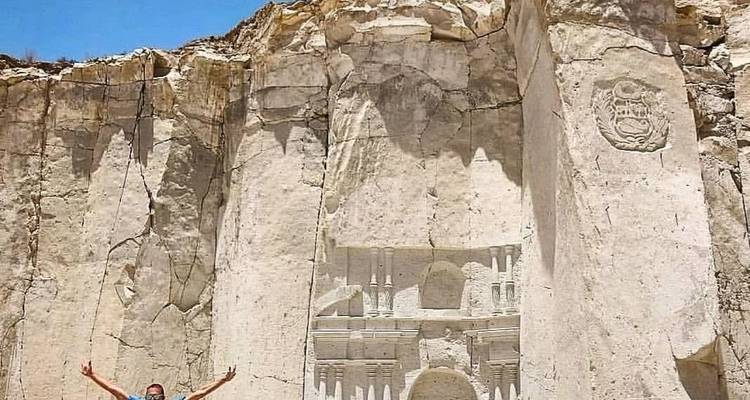 Paroi rocheuse avec des gravures et un touriste debout devant.
