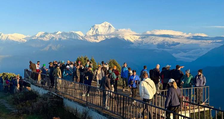 Des touristes se sont rassemblés à un point de vue avec des montagnes, possiblement Poon Hill.