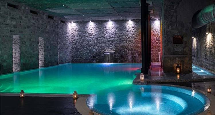 Binnenzwembad met sfeerverlichting en stenen muren.