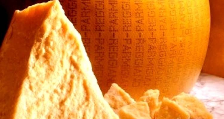 Close-up van een kaaswiel met ingegraveerde tekst erop, omringd door stukjes kaas.