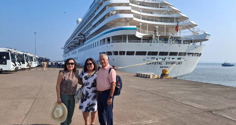 Three people standing in front of a large cruise ship