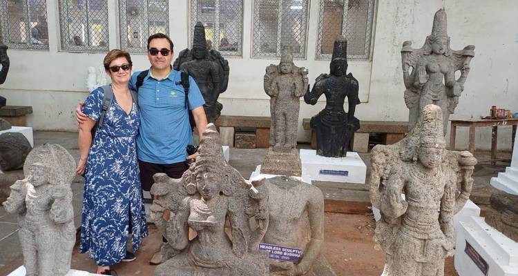 Stel poseert voor verschillende stenen sculpturen in een museum.