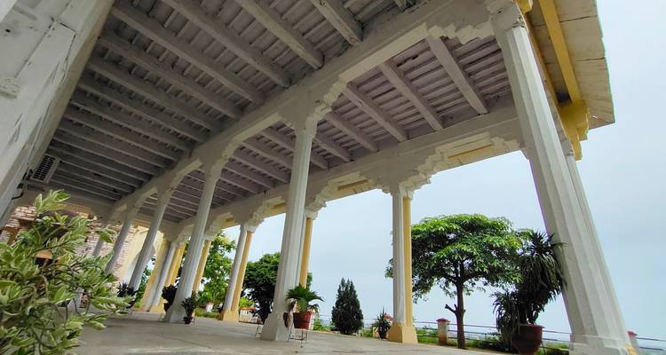 Overdekte loopbrug met bomen en leuningen, witte zuilen and plafonds.