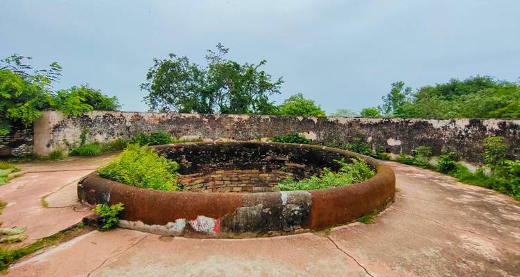 Een ronde stenen structuur met omringende lage muren.