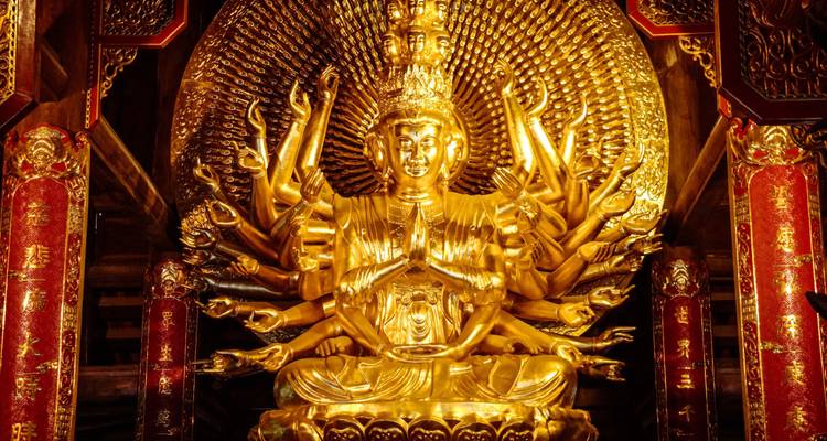 Ornate multi-armed golden Buddha statue inside Bai Dinh Pagoda