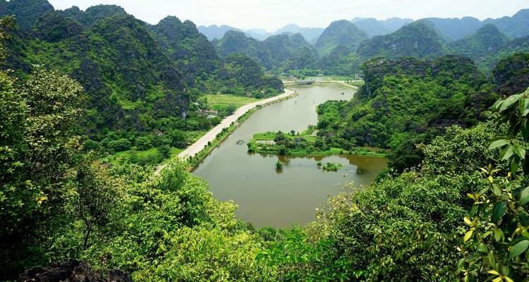 Green karst mountains overlooking a tranquil lake and winding road through the valley