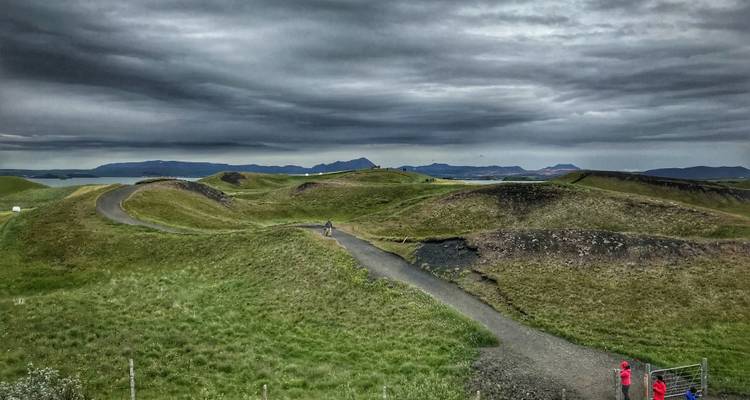 Wandelpad door een heuvelachtig landschap onder een dramatische bewolkte hemel.
