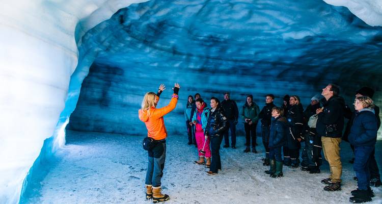 Groep mensen die een ijsgrot verkent met een gids.