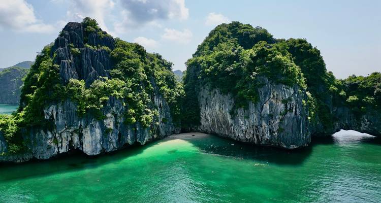 Islas de piedra caliza espectaculares cubiertas de exuberante selva enmarcan una pequeña playa de arena blanca y agua esmeralda.