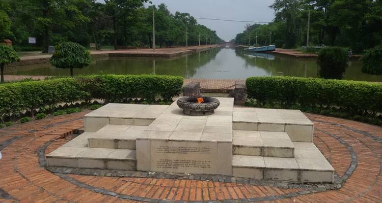 Eine ewige Flamme brennt auf einer Steinplattform neben einem langen Kanal im Lumbini-Garten.