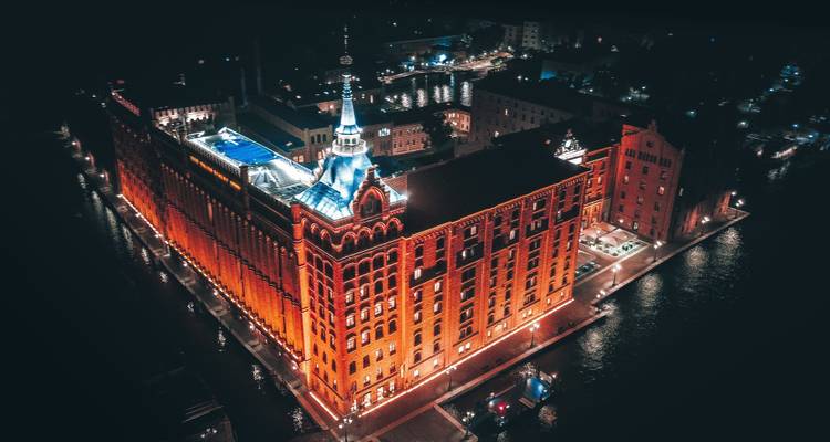 Illuminated historic building at night surrounded by water.