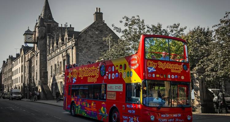 Stadtrundfahrtbus auf einer Straße mit historischen Gebäuden.