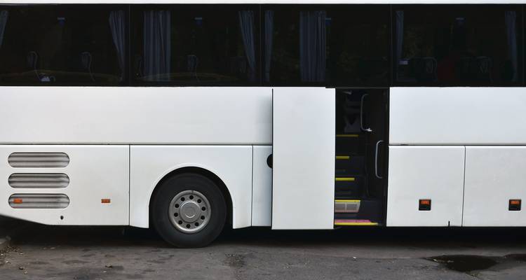 Witte tourbus geparkeerd met open deur.