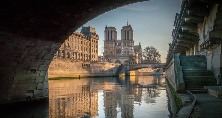 Cathédrale Notre-Dame vue de sous un pont avec des reflets sur la rivière.