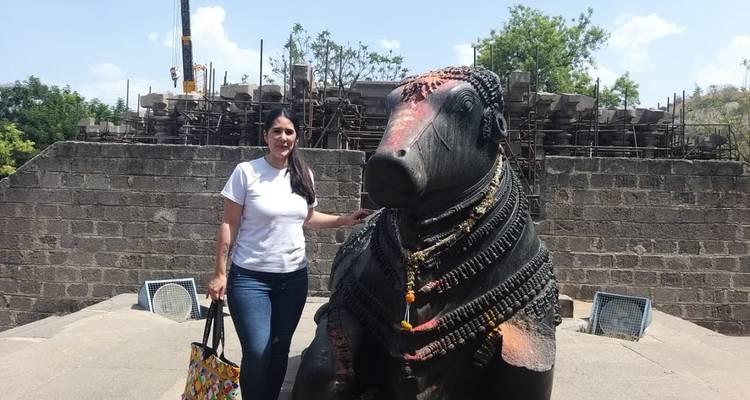 Toerist naast een groot stenen beeld buiten.