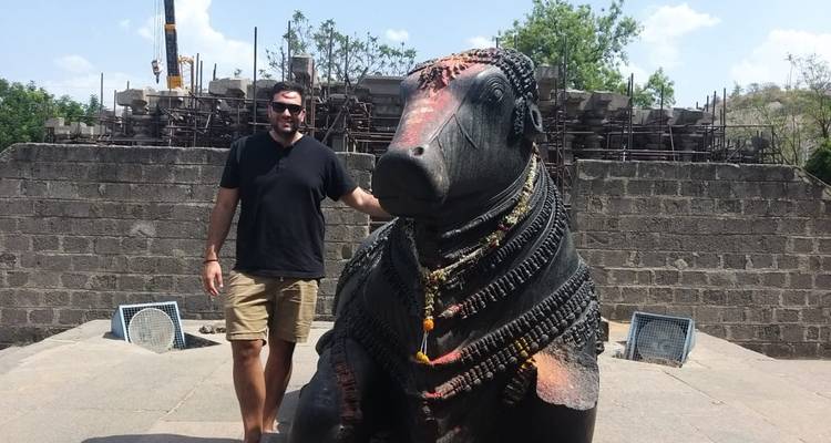 Man die poseert met een groot stenen standbeeld.