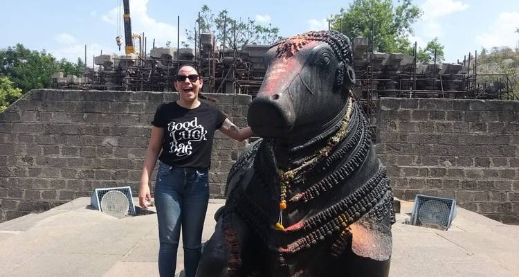 Vrouw die naast een groot stenen beeldhouwwerk staat.