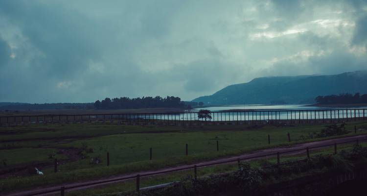 Vue d'un lac avec des collines environnantes sous un ciel nuageux