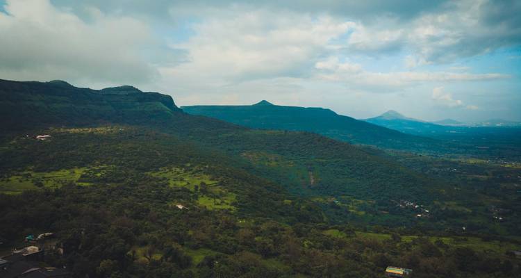 Vue montagneuse avec verdure et un ciel nuageux