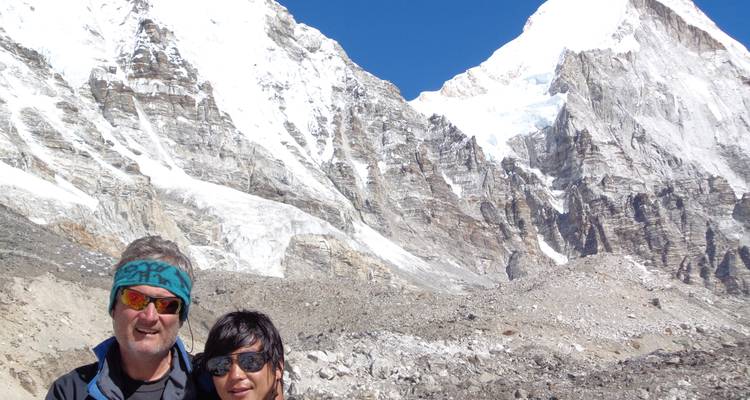 Zwei Menschen stehen vor einer verschneiten Bergkette im Hintergrund.