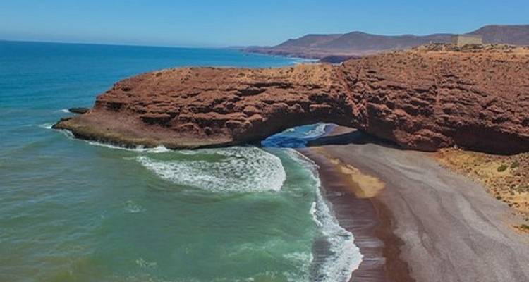 Arch-shaped rock formation by the sea.