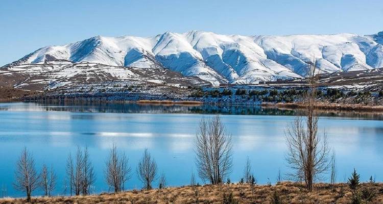 Snow-capped mountains reflecting in a lake.