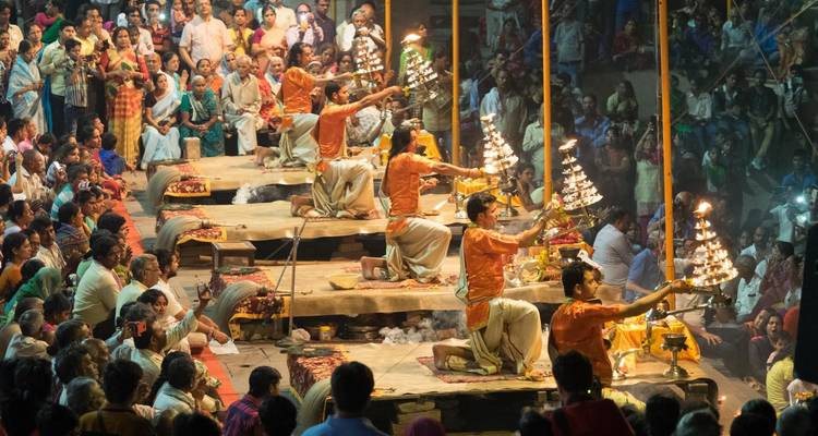 Groep mensen die het Ganga Aarti-ritueel uitvoeren op de rivieroever in Varanasi.