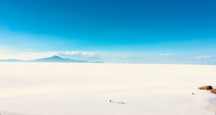 Vasto salar bajo un cielo azul despejado con montañas distantes.