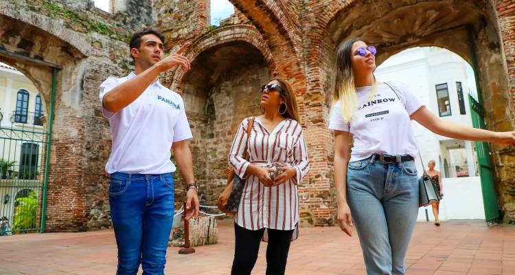 Un guía les explica las ruinas de ladrillo del Casco Viejo a dos turistas bajo los arcos y la luz solar brillante.
